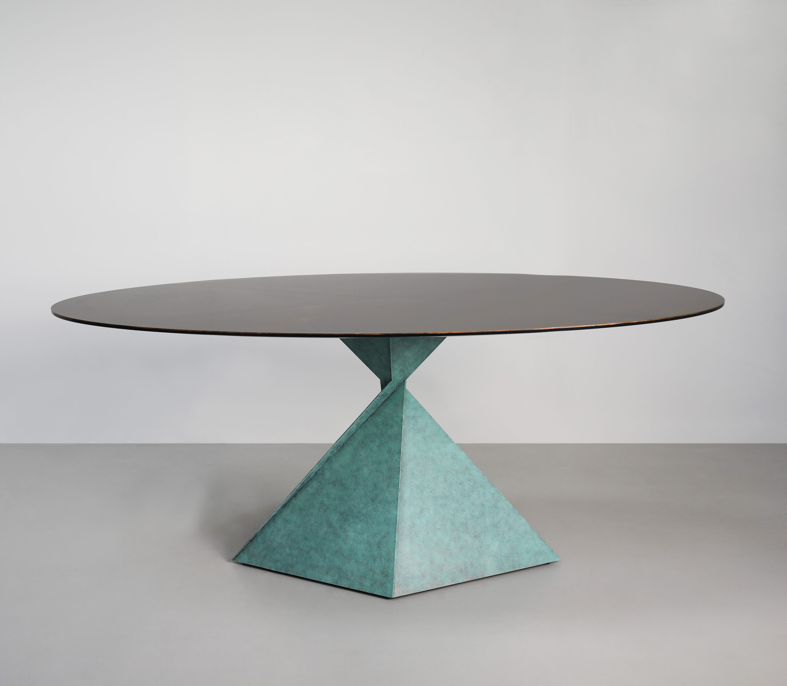 Avebury oval dining table in steel finished in ‘Verdigris’ with a segmented mottled bronze and brass top